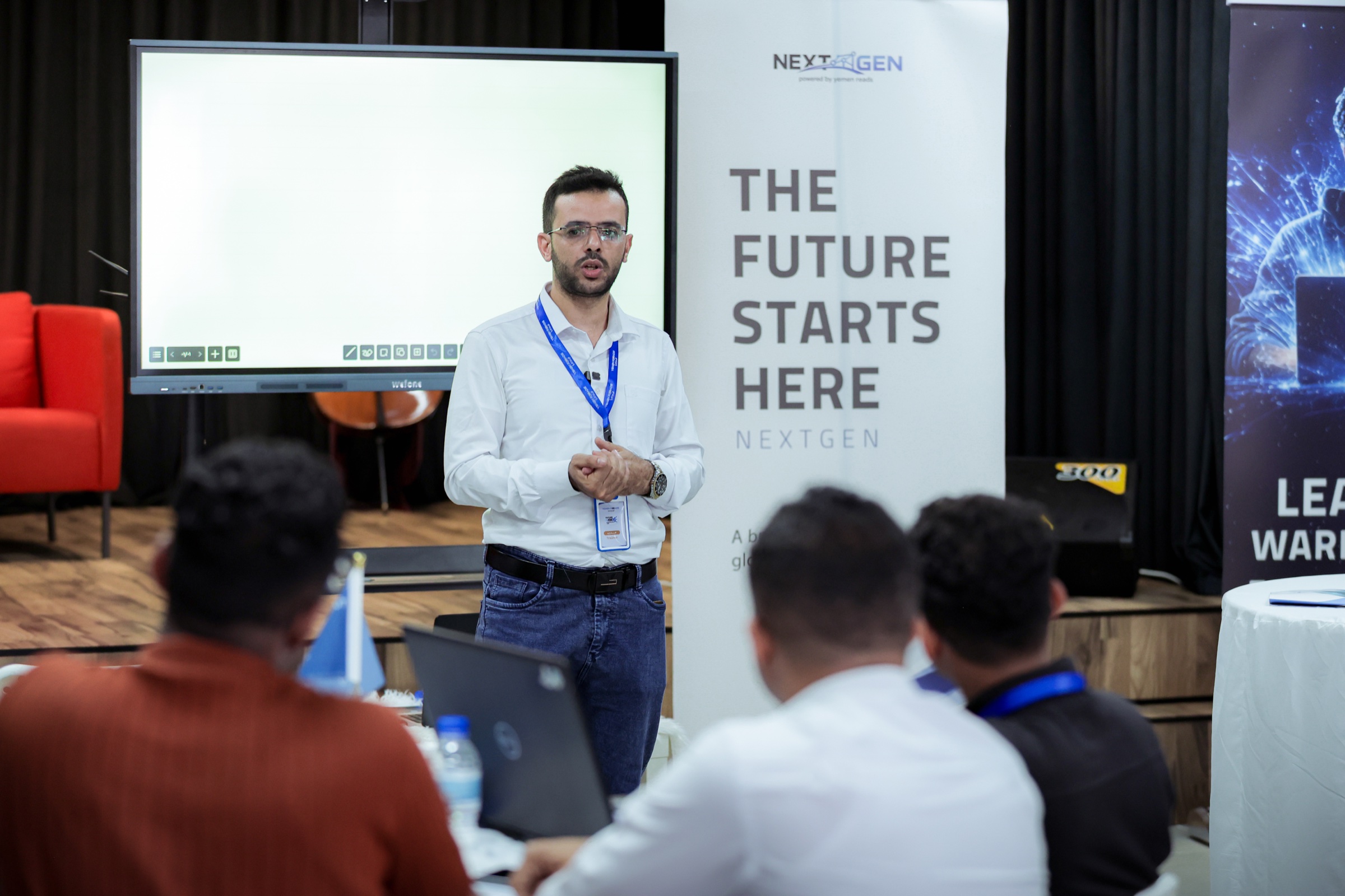 A NEXTGEN facilitator leading a session beside The Future Starts Here banner